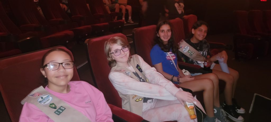 4 Girl Scouts sitting in a row at the planetarium.